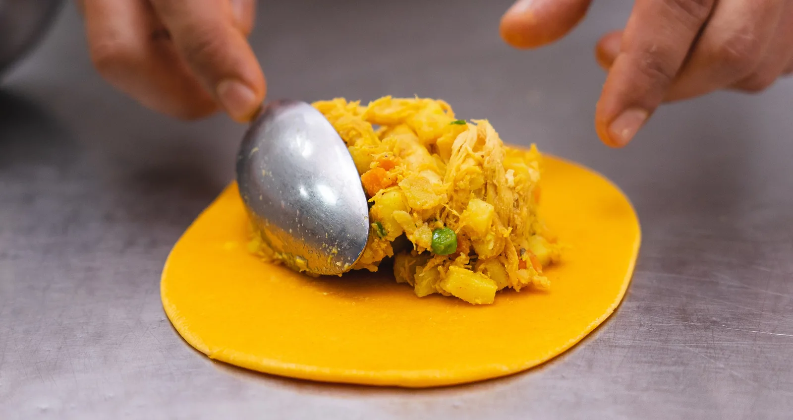 Manos cerrando el repulgue de una salteña
